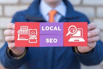 Man holding colorful blocks with icons and inscription: LOCAL SEO. Local search marketing e-commerce. Concept of local seo strategy, local search optimization. - obrazy, fototapety, plakaty