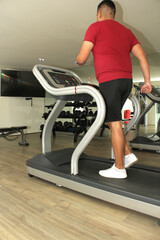Forty-year-old dark-haired Latino adult man exercises his legs on the treadmill as a treatment for...