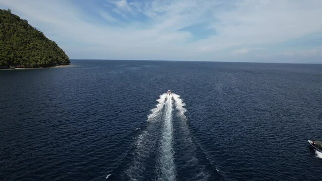 Following dhingy with a view on blue ocean and tropical Mansuar island in Raja Ampat, Papua, Indonesia