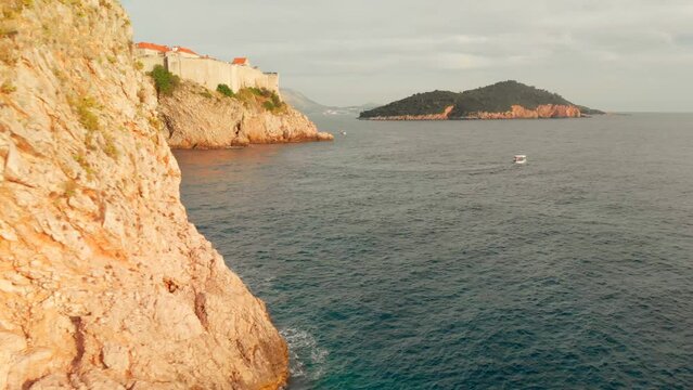 A reveal shot of the Dubrovnik Old Town. The walls of the old town can be seen from a low flying drone shot