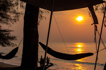 A relaxing hammock in the morning when the sun is rising on a beautiful sandy beach in summer.