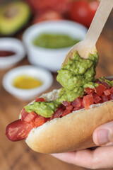 Completo Italiano: Vertical close-up. Adding avocado, with wooden spoon, over tomato and vianesa on...