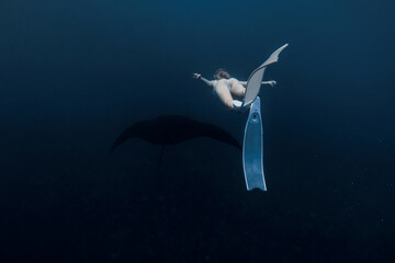 Woman freediver with white fins swim with manta ray. Freediving with manta rays on deep