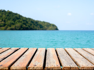 Obraz premium Empty old wooden desk template on tropical sea, island and summer sky background. Brown top table or grunge wood plank space for place products, packaging for summertimes advertising campaign.