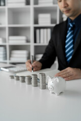Image of businessman, bookkeeper with stacks of coins Piggy bank and write accounts Ladder planning, savings for the future, retirement funds, financial investment business.