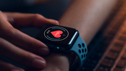 Close up of hand touching smartwatch with heart rate checking app on the screen.