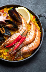 Traditional spanish seafood paella in the fry pan on a black background.