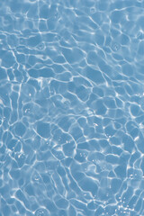 Blue water with ripples on the surface. Defocus blurred transparent blue colored clear calm water surface texture with splashes and bubbles. Water waves with shining pattern texture background.