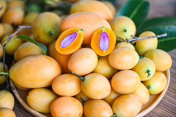 Marian plum fruit and leaves in plate on wooden background, tropical fruit Name in Thailand Sweet Yellow Marian Plum Maprang Plango or Mayong chid