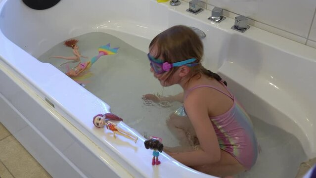6 year old girl practicing diving and holding her breath while using googles inside her bathtub at home