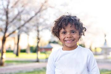 Charming Beautiful Black young boy with a playful smile and curly hair. Outdoor candid portrait of a natural beauty	