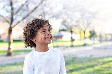Charming Beautiful Black young boy with a playful smile and curly hair. Outdoor candid portrait of a natural beauty	