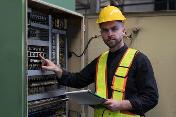 Male electrician worker checking, repair, maintenance electric system of CNC machine in factory. Male electrician engineer inspecting quality electric during manufacturing process