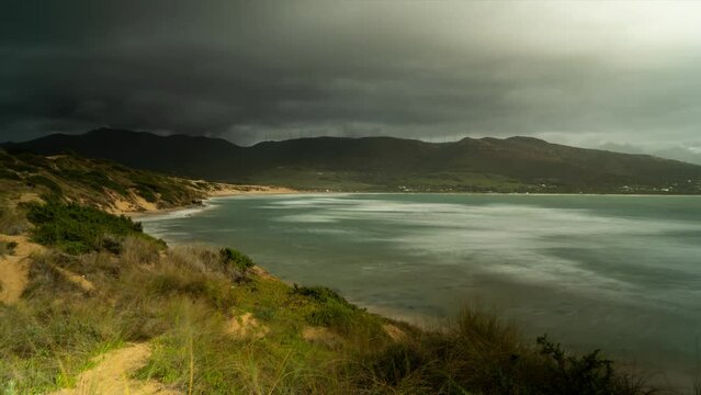 Extreme dark clouds flowing over island coastline and beach, time lapse view