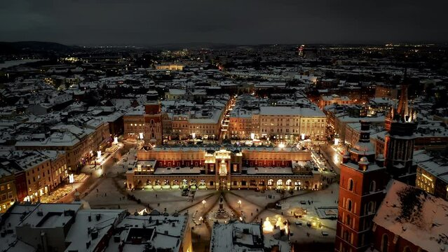 Aerial view of snow covered Old Town (Krakow city center - Main Square, Mariacki Church, Sukiennice - Cloth Hall and Town Hall) and Main Market Square with Christmas stalls at night in Krakow, Poland