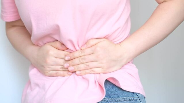 Female hands squeeze the stomach on white background, the concept of abdominal pain.