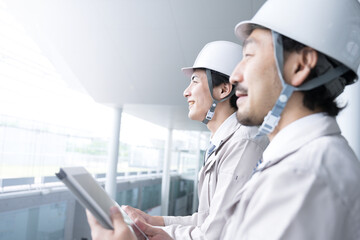 逆光の中未来を見つめる上半身の作業員　2人の横顔のアップ