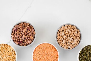 Legumes in glass jars top view on white background. Vegetable protein, healthy eating. Copy space