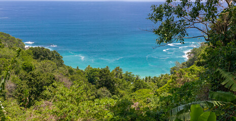 Fototapeta na wymiar looking down on Freedom Beach Phuket Thailand. Magnificent colours in the sky and turquoise blue waters and white sandy beach through the lush green colours of the rainforest 