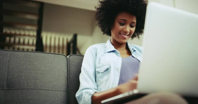 Laptop, phone and a woman on home sofa for communication, internet connection or chat. African person with tech for social media, online search and remote work or typing email for blog on website