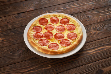 Tasty delicious pepperoni pizza with salami on the dark wooden rustic background, street food and delivery concept for menu design