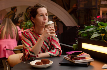Brunette woman drinking coffee and eating chocolate dessert alone in cafe