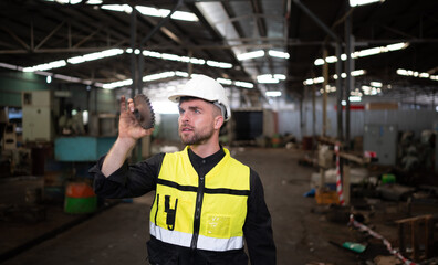 An engineer visually inspects a mechanical sprocket for damage.