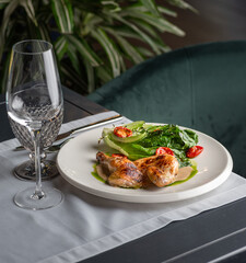 Half of a roasted chicken, on plate with herbs and tomatoes.