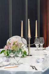 wedding decorations. Served wedding table with decorative natural flowers and. holiday details. flower arrangement, plates and candles in candlesticks, glasses