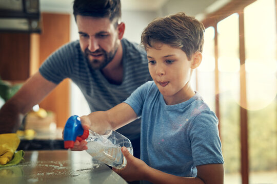 Family, father and son cleaning the kitchen counter, development and growth at home. Parent, male child and dad with kid, support and teaching with chores, helping and learning with responsibility