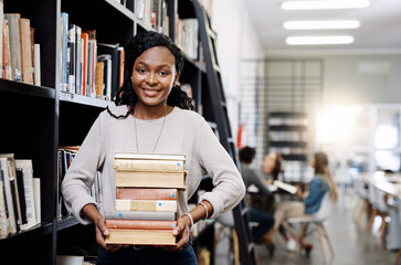 Black woman, student with book stack in library and research for project, study and learn on university campus. African female person smile in portrait, education and scholarship with course material