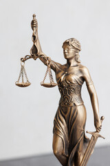 themis goddess of justice statuette on light gray background. symbol of law with scales sword in...