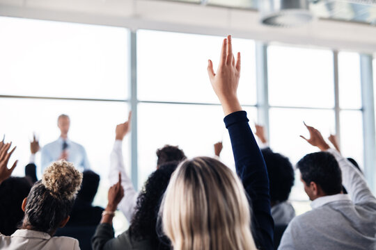 Conference, convention and business people with hands for a question, vote or volunteering. Corporate event, meeting and hand raised in a training seminar for questions, voting or audience opinion