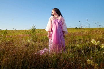 Young plump curvy beautiful teenage girl in a field or meadow on a sunny summer day in the evening sunset sun. Plump black-haired and black-eyed oriental model from the east fairy tale