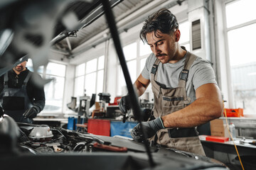 Fototapeta na wymiar Two male mechanics repairing car in car service