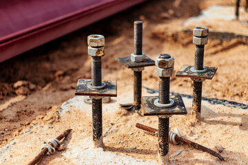 Close up the anchor bolts in concrete base of new edifice with reinforcement at building site.