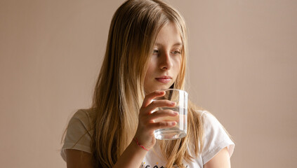 Blonde girl drink a glass of water at home close up