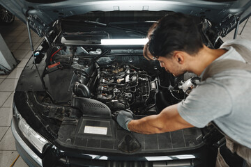 Fototapeta na wymiar Young male mechanic examining engine under hood of car at the repair garage