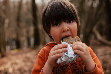 child eating sandwich in a forest