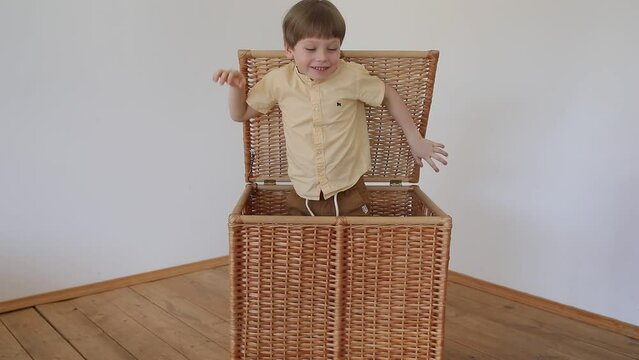 A boy peeks out of a wicker basket