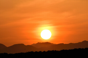 Fototapeta premium 山の向こうへと沈む夕日