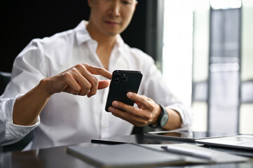 Close-up image of a businessman checking messages on hias smartphone at his desk