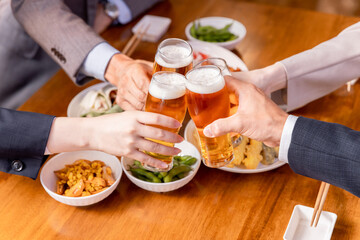 居酒屋で忘年会・新年会・飲み会・宴会をする仕事仲間・同僚・上司部下の男女
