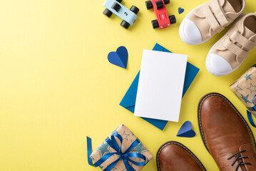 Toddler son cheers on Dad for Father's Day. Overhead shot of father's shoes, son's sneakers, car toys, handmade postcard, and gift box on yellow background with a blank space for text or advert