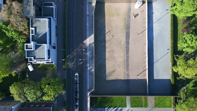GDR watchtower next to Tram. Spectacular aerial top view flight 
Berlin Wall Memorial Border crossing zone, city district, Germany spring 2023. vertical bird's eye view drone
4k uhd cinematic footage.