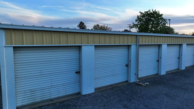 Old storage units on gravel lot. Aerial rising shot of self storage warehouse buildings.