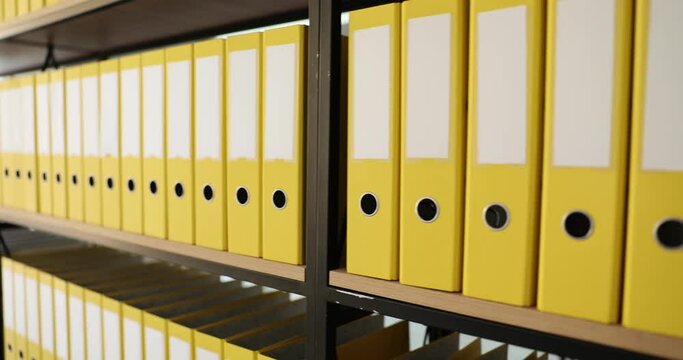 Yellow organized folders structure with materials on shelf of rack in company premise. Concept of saving data in office building archive storage slow motion