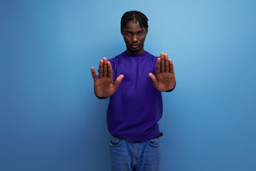 Fototapeta premium doubtful dark-skinned american african young brunette man with dreadlocks in a blue hoodie