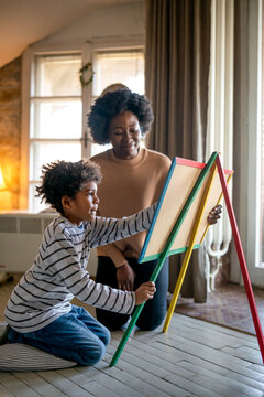 Happy adorable african american boy enjoying studying with mommy's assistance at home