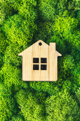 Naklejka premium Miniature wooden house on green moss. concept of selling, insuring or renting real estate. vertical photo